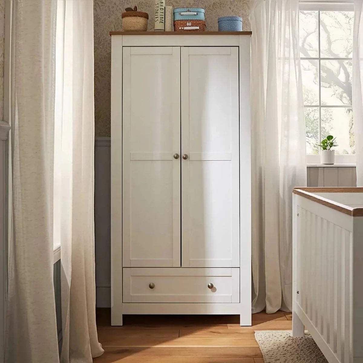 White wooden wardrobe with two doors and bottom drawer; brass knobs and trim.