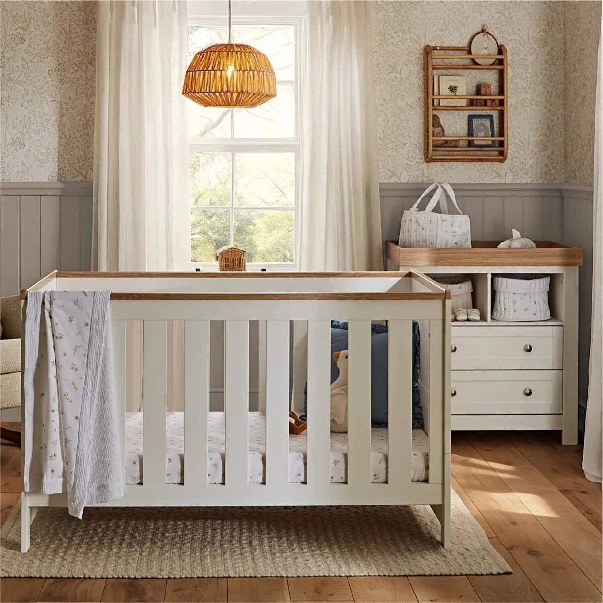 White nursery cot with slatted sides and light wooden top rails