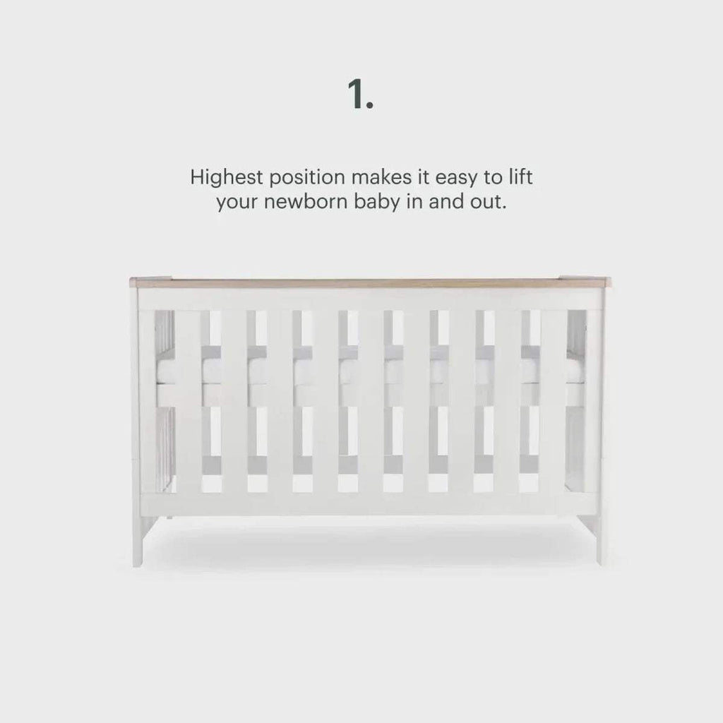 White cot with slatted sides at highest position, side view with height note