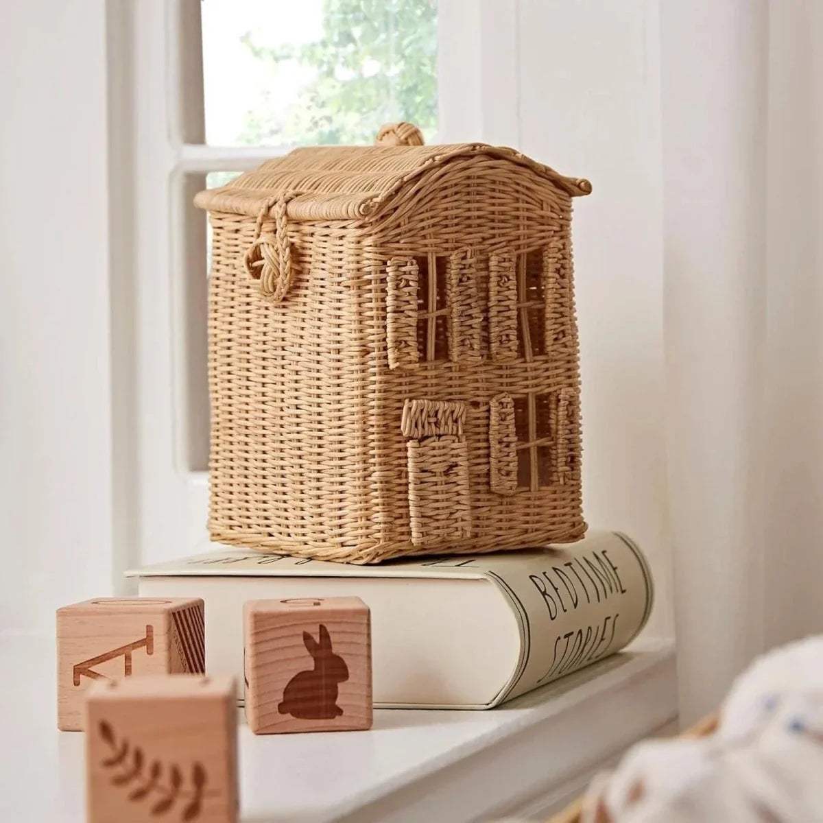 Tan wicker storage basket with loop handle and house-style front detail