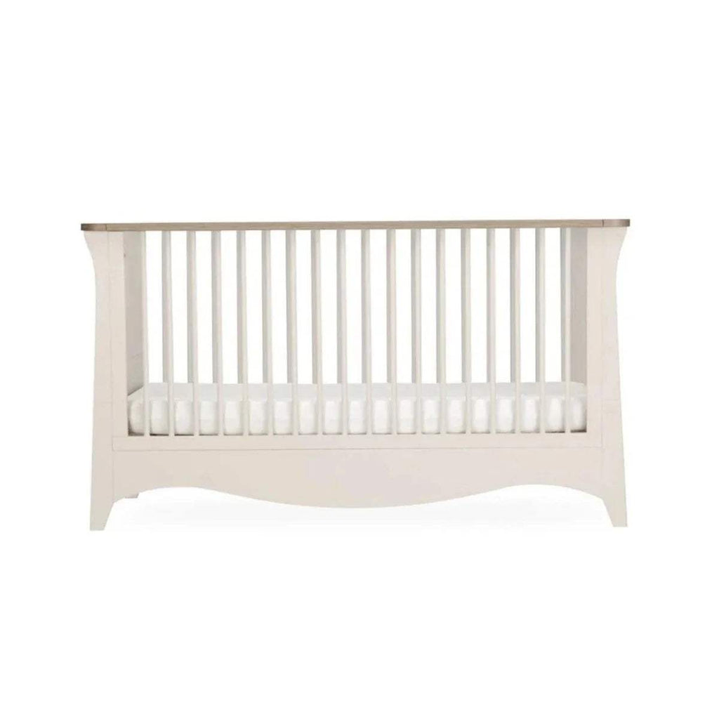 White nursery crib front view with vertical slats and curved skirt base