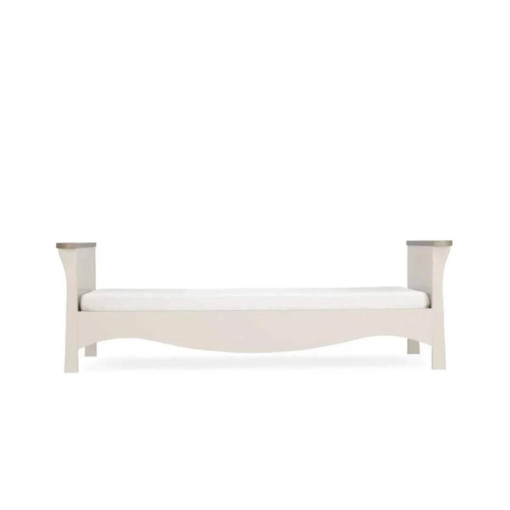 White toddler bed frame with curved rails and short legs, side view