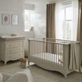White nursery crib with vertical slats and matching 3-drawer dresser, styled with soft textiles