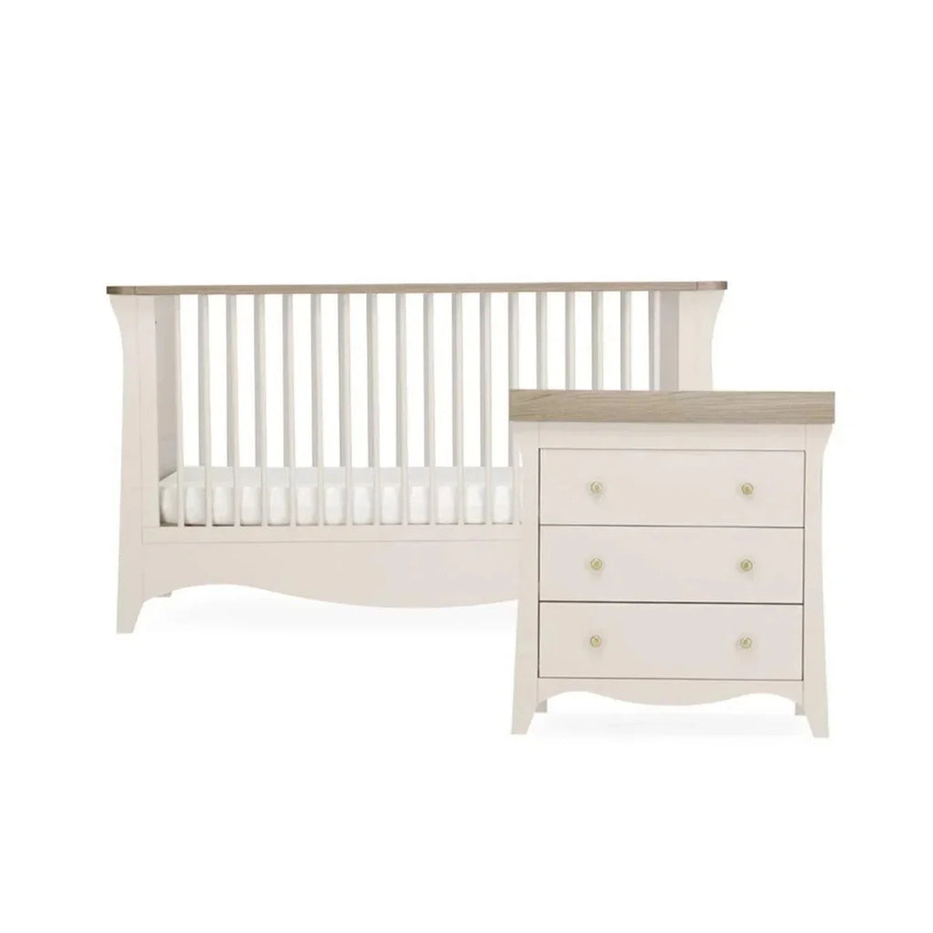 White nursery crib with vertical slats and matching 3-drawer dresser, studio view