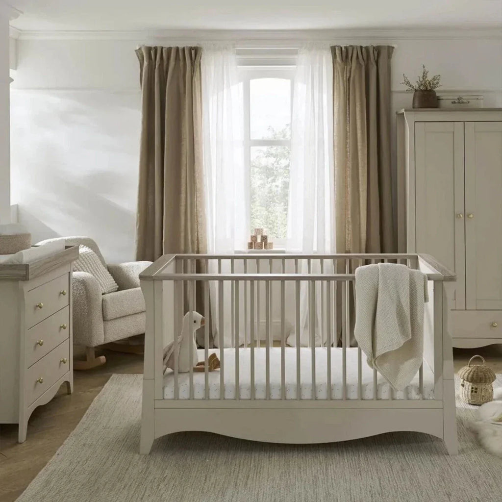 White nursery crib with rails and matching dresser with drawers, styled in a nursery