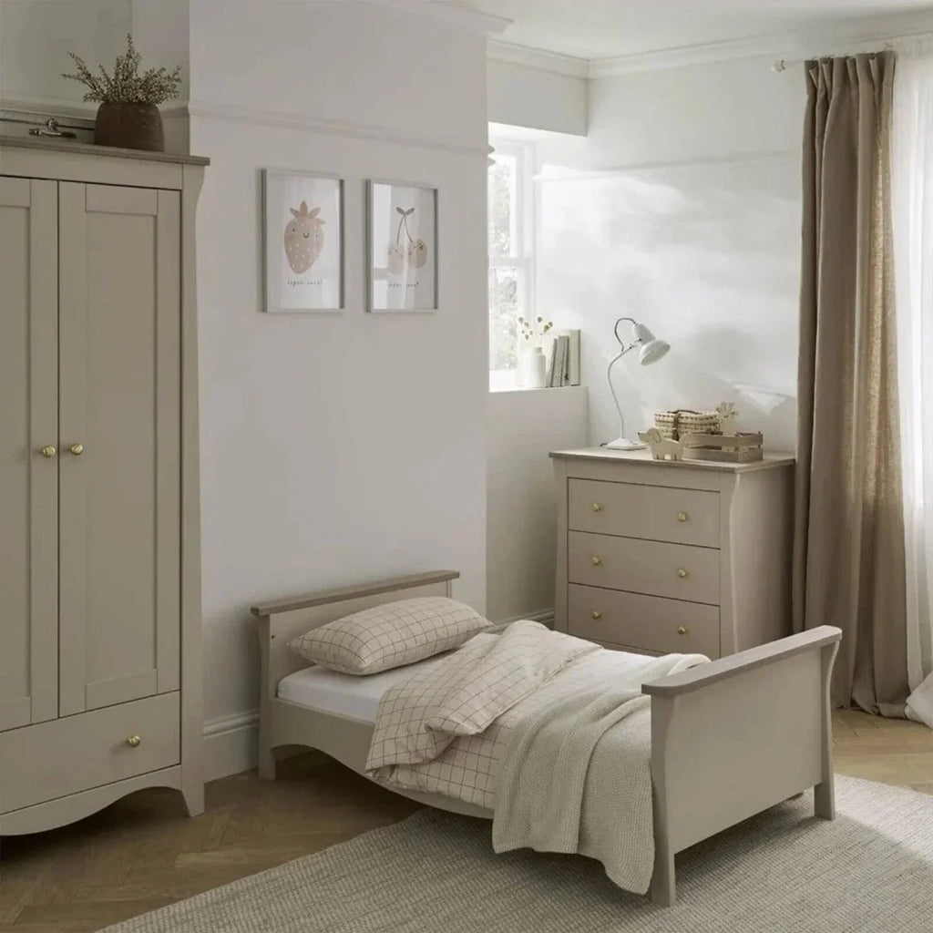 Light-colored toddler daybed with side rails and matching dresser, nursery layout