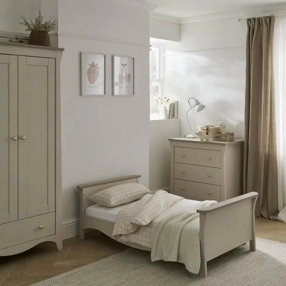 Light-colored toddler daybed with side rails and matching dresser, nursery layout