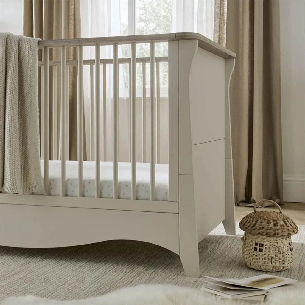 White nursery crib with raised guard rails and side panel, close-up angle