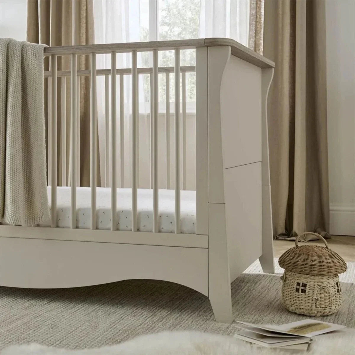 White nursery crib with raised guard rails and side panel, close-up angle