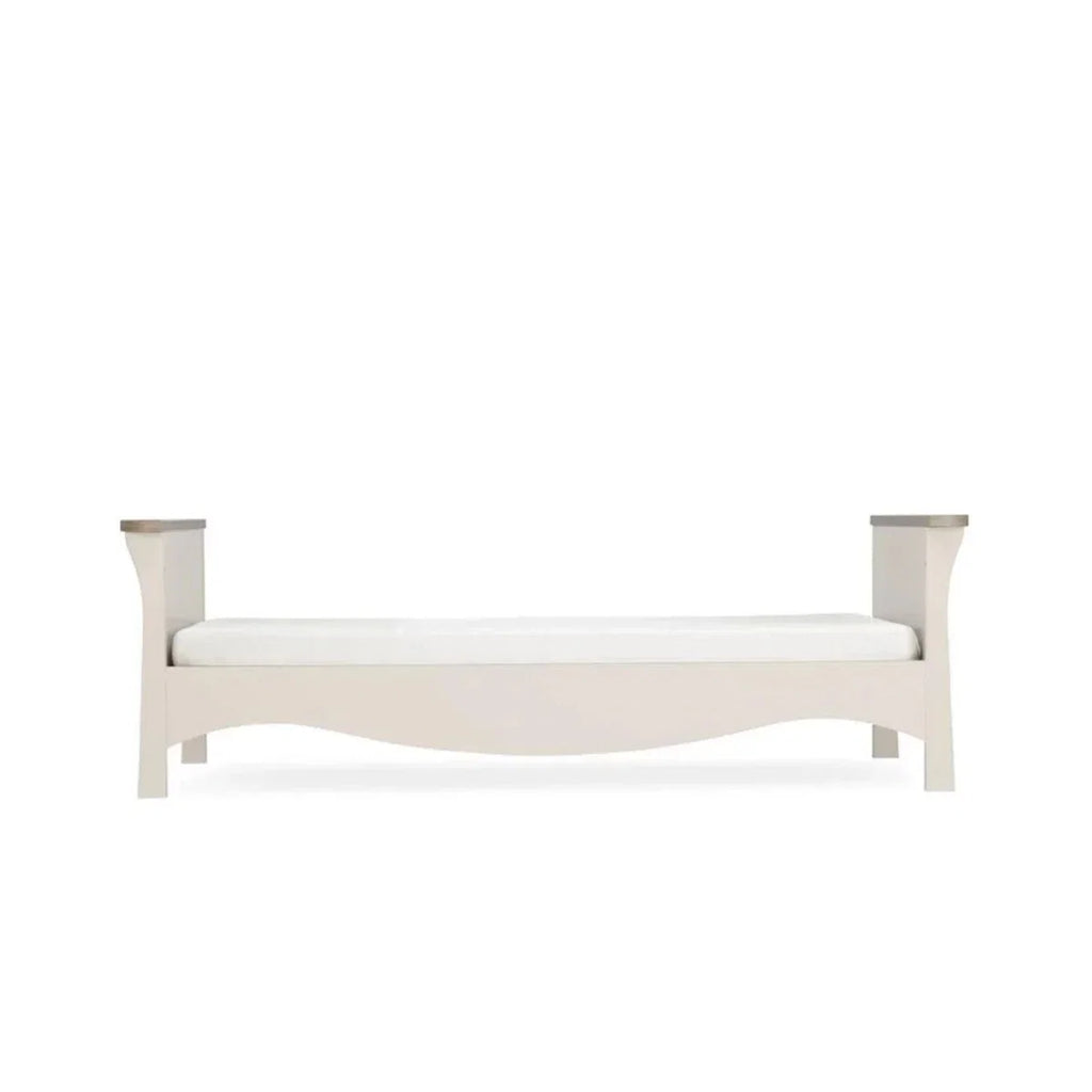 Light-colored toddler daybed frame with curved ends and side posts, front view