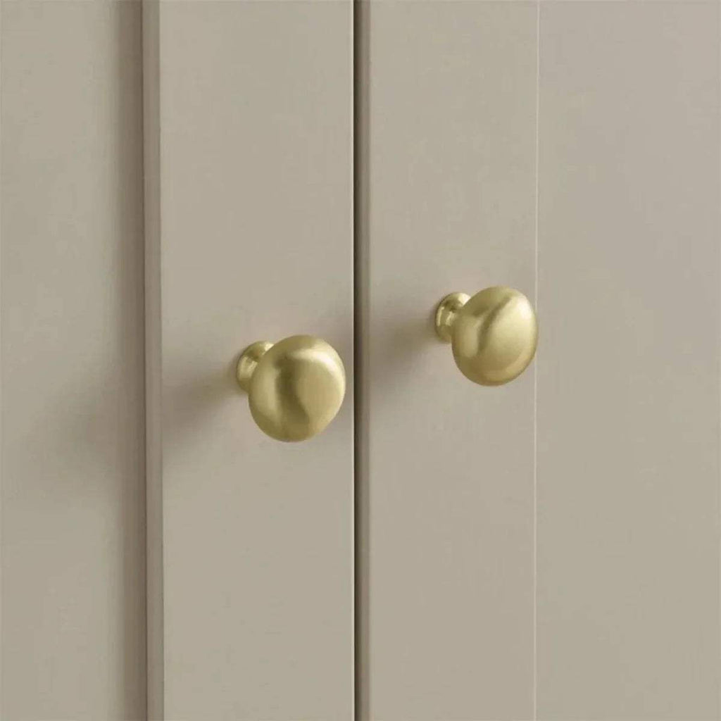Gold round knobs on a white wardrobe door