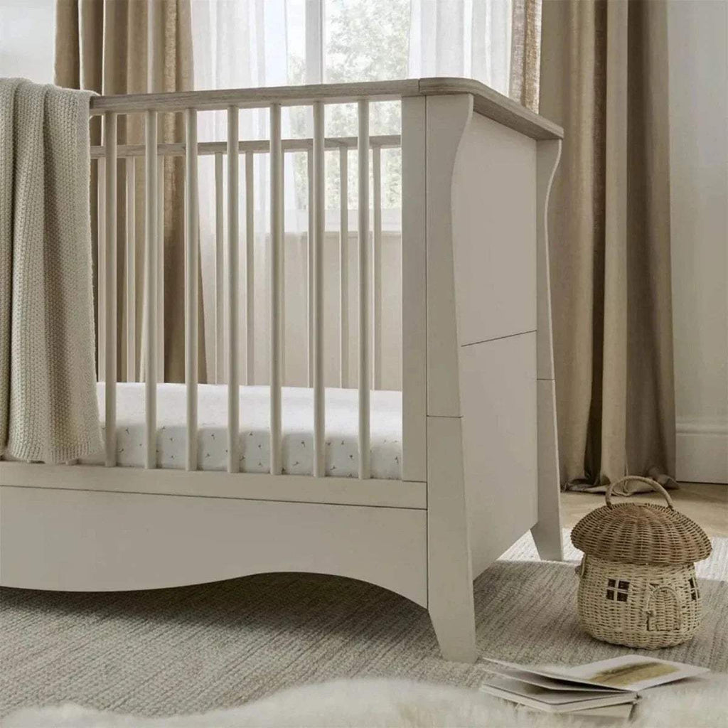 White cot bed with curved end panels and vertical slatted rail, side view