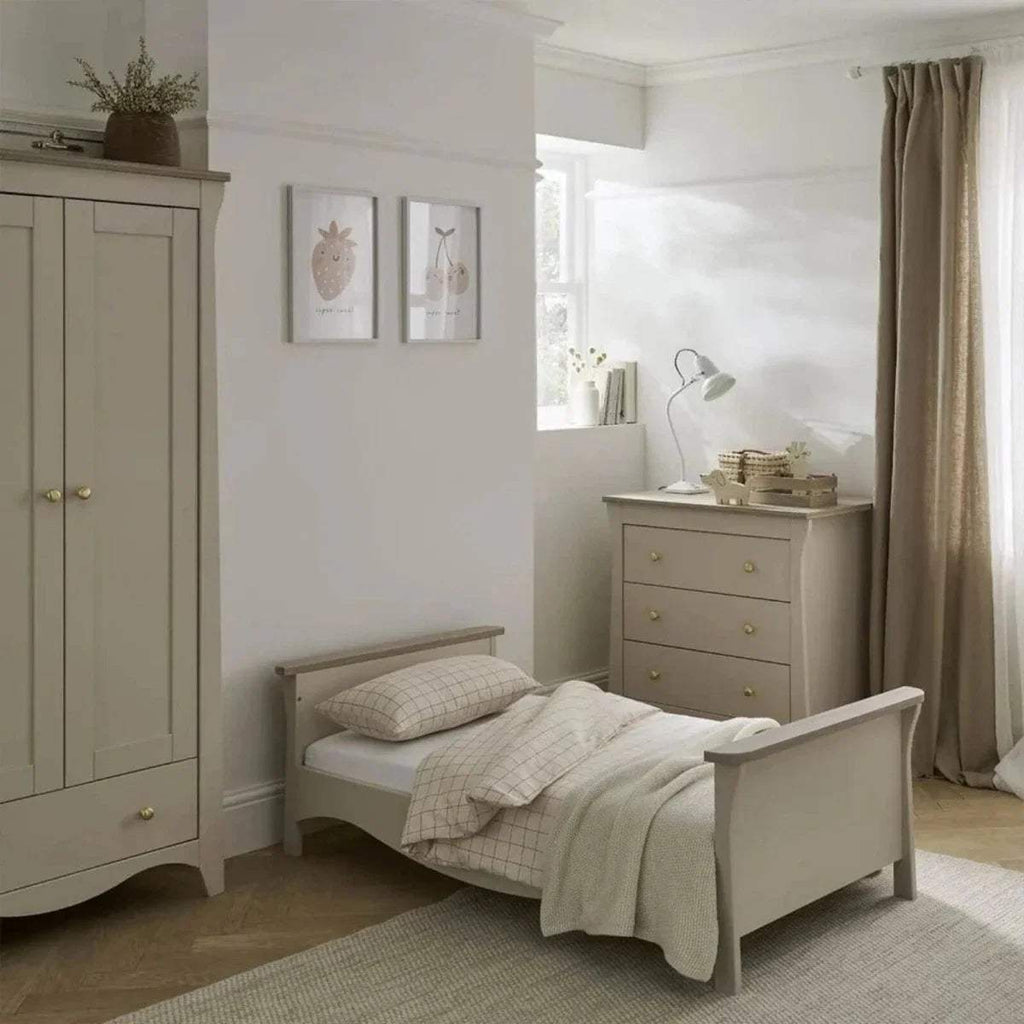 White cot bed in nursery with slatted guard rail and neutral bedding