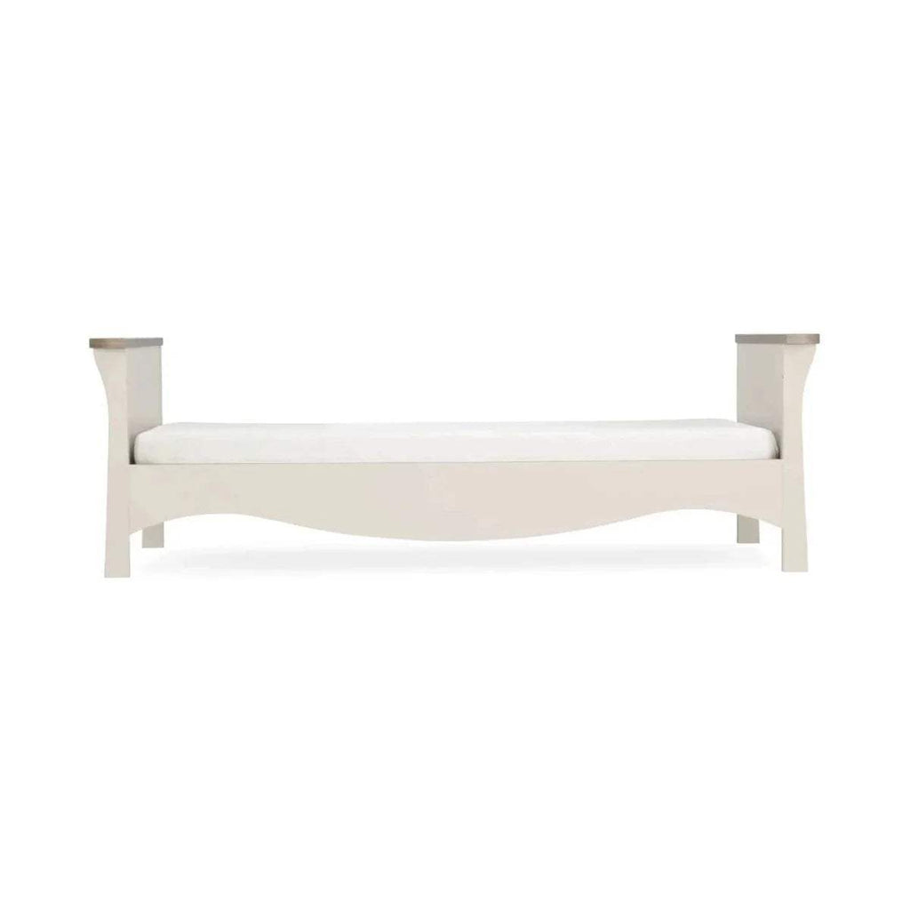 Cream toddler bed frame with slatted sides and low footboard, simple paneled design