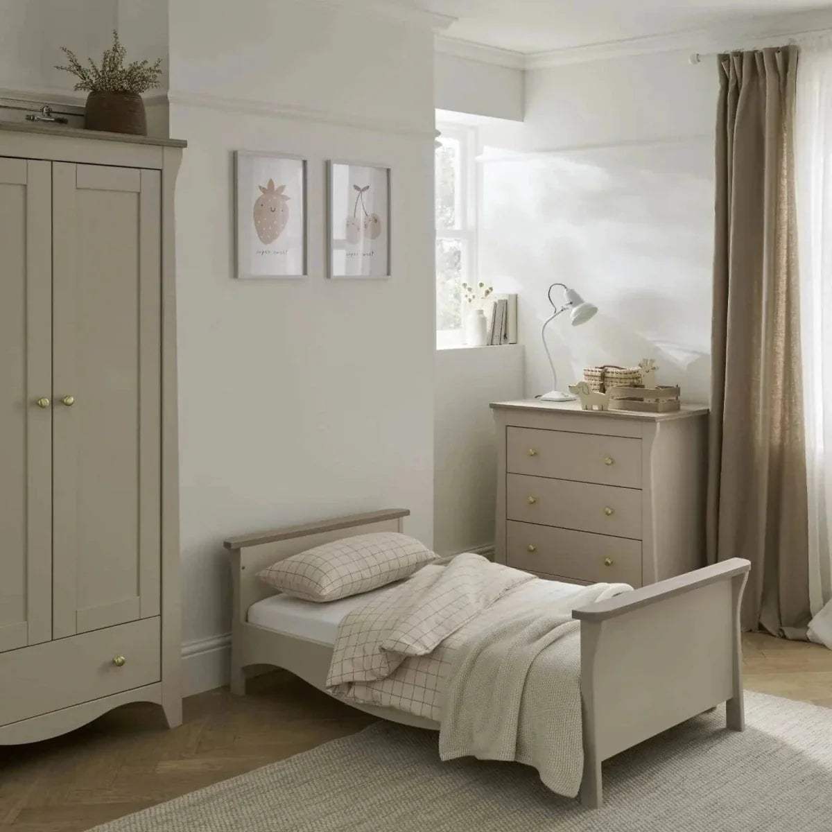 Cream toddler bed with paneled headboard, grid bedding, and folded light throw