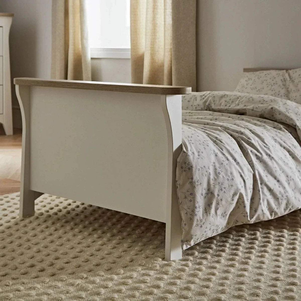 White toddler bed with panel headboard and side rail, side view