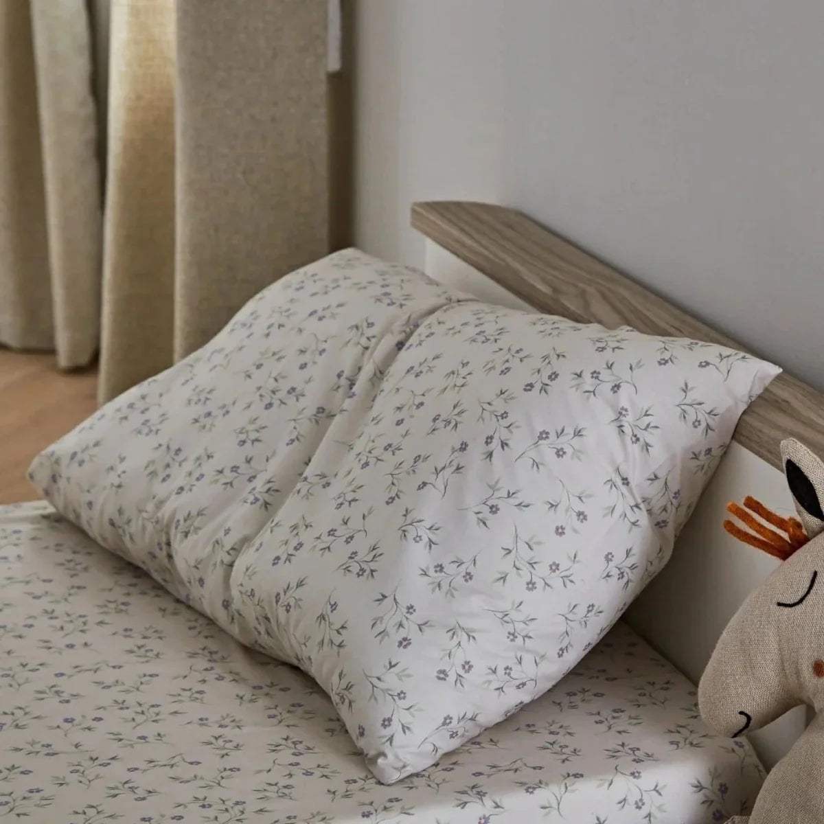 White toddler bed with floral-pattern pillows and duvet on the mattress
