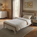 Cashmere-ash single bed with white pillows and upholstered headboard