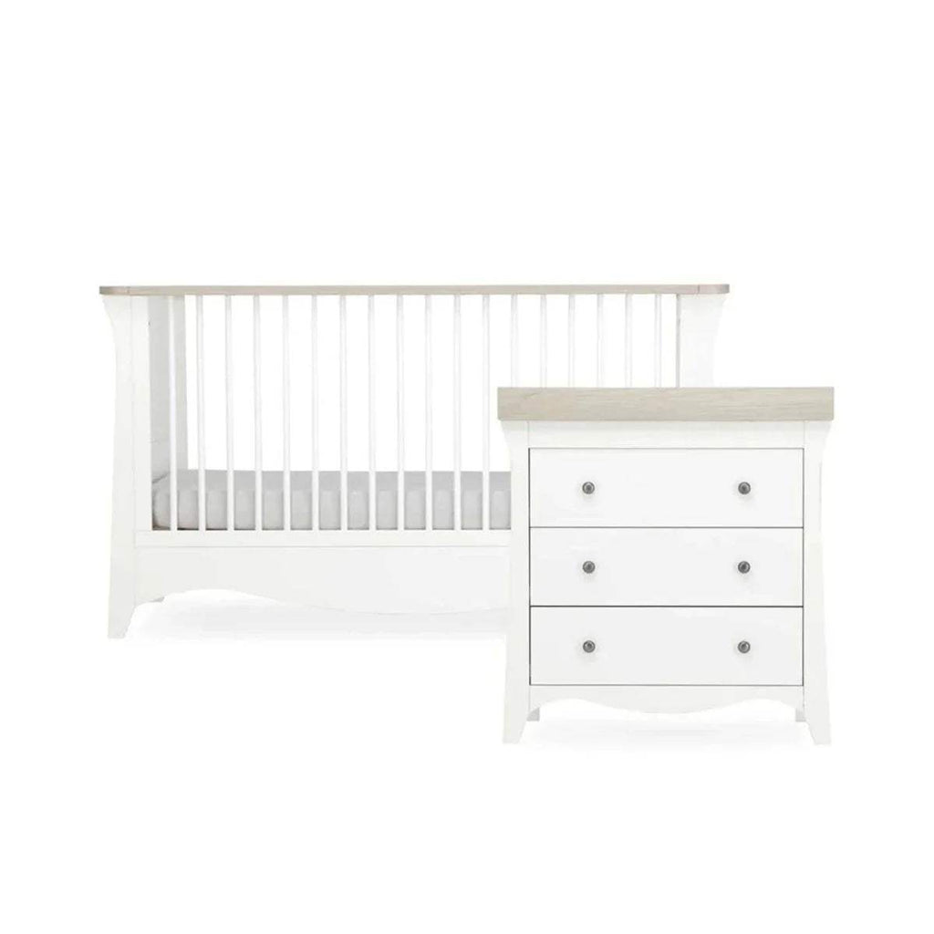 White nursery crib with slat rail and matching white dresser with drawers