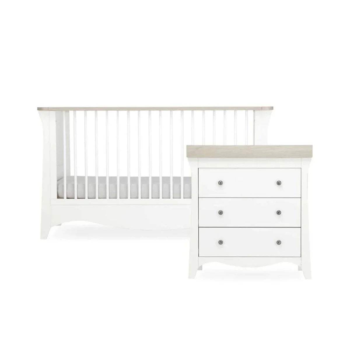 White nursery crib with slat rail and matching white dresser with drawers