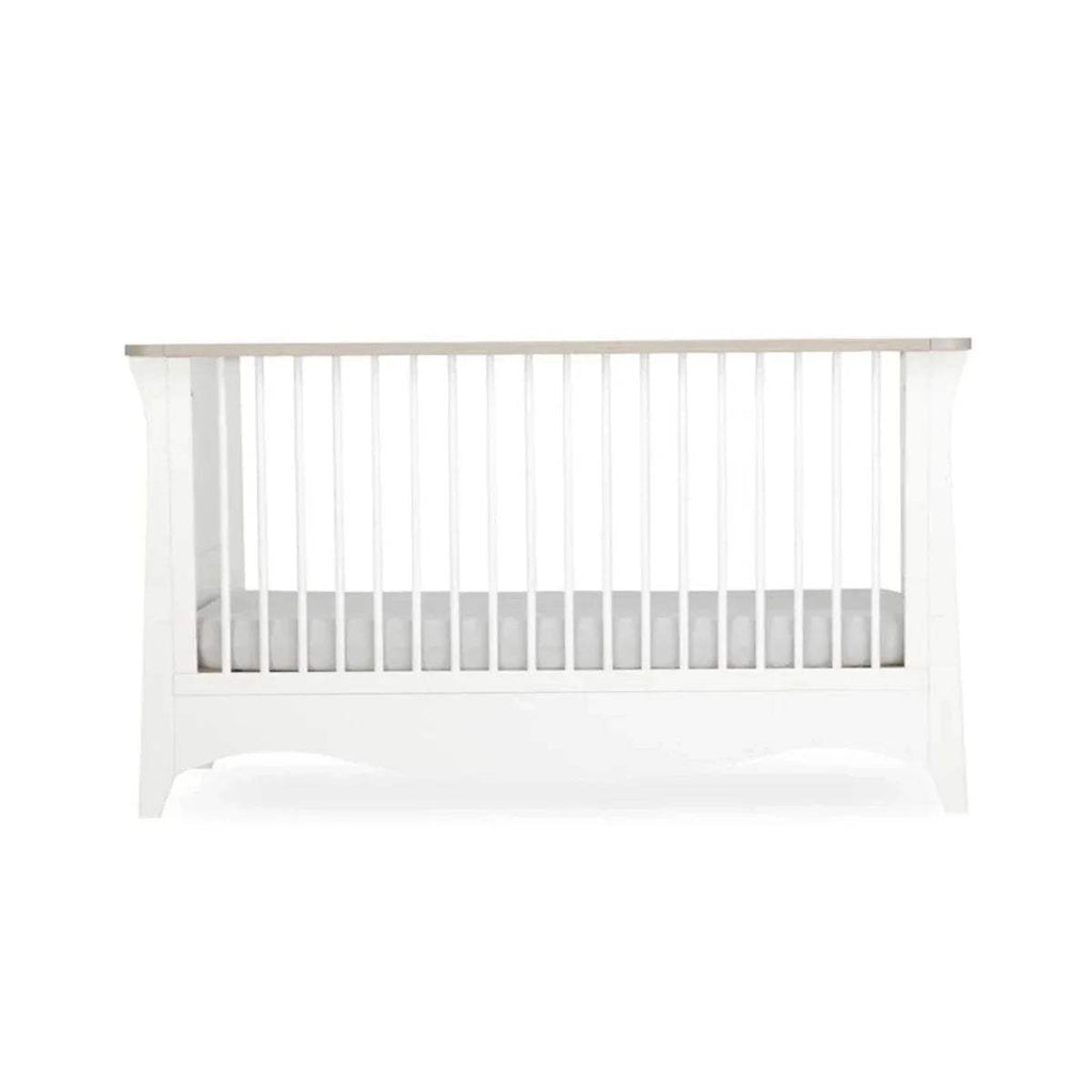 White nursery crib with vertical slats and solid lower panel