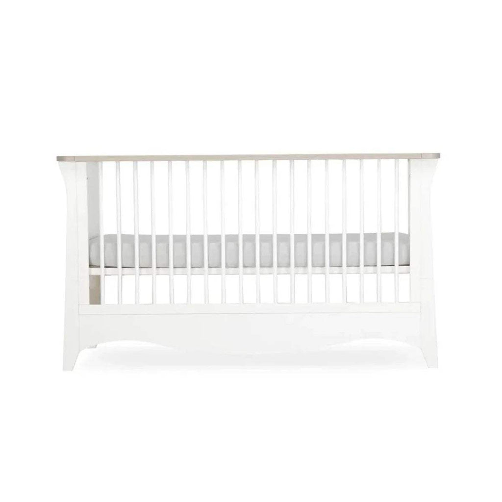 White nursery crib with vertical slats and wide lower base panel