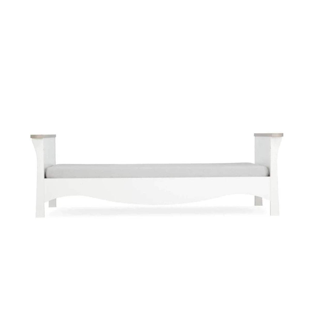 White nursery bed with four posts and horizontal slats, simple panel headboard