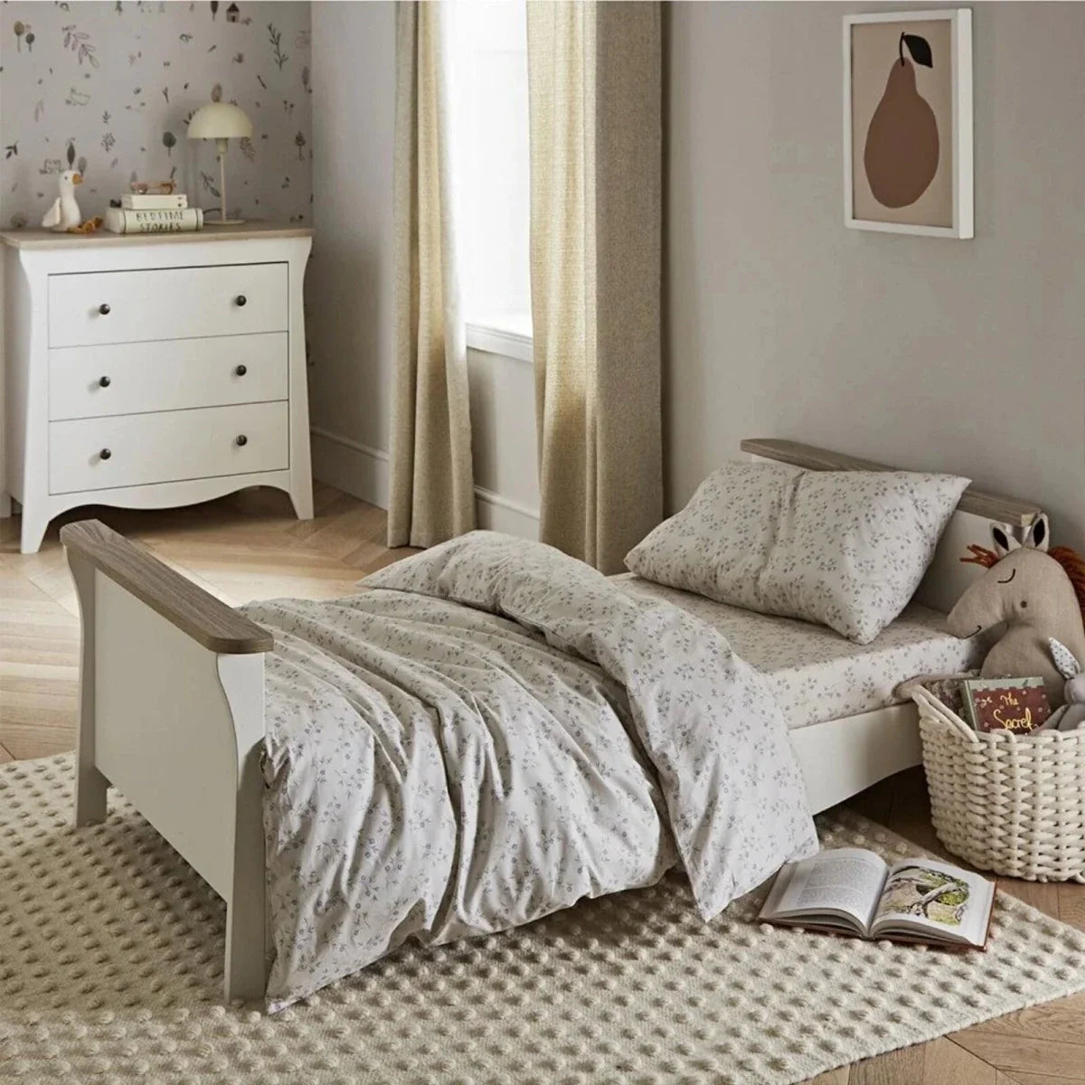 White nursery daybed with ash wood side rails and patterned pillows.