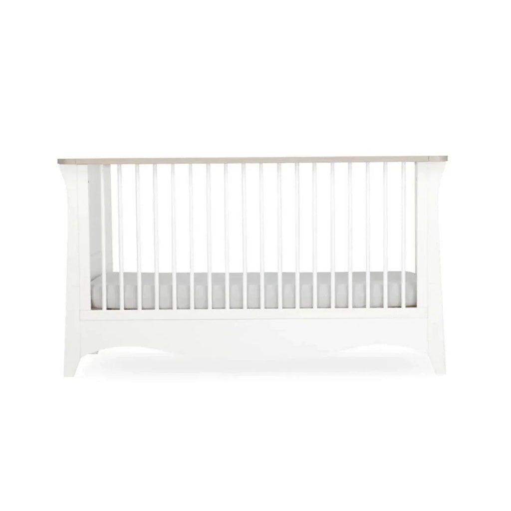 White nursery crib with vertical slat panel and padded mattress base