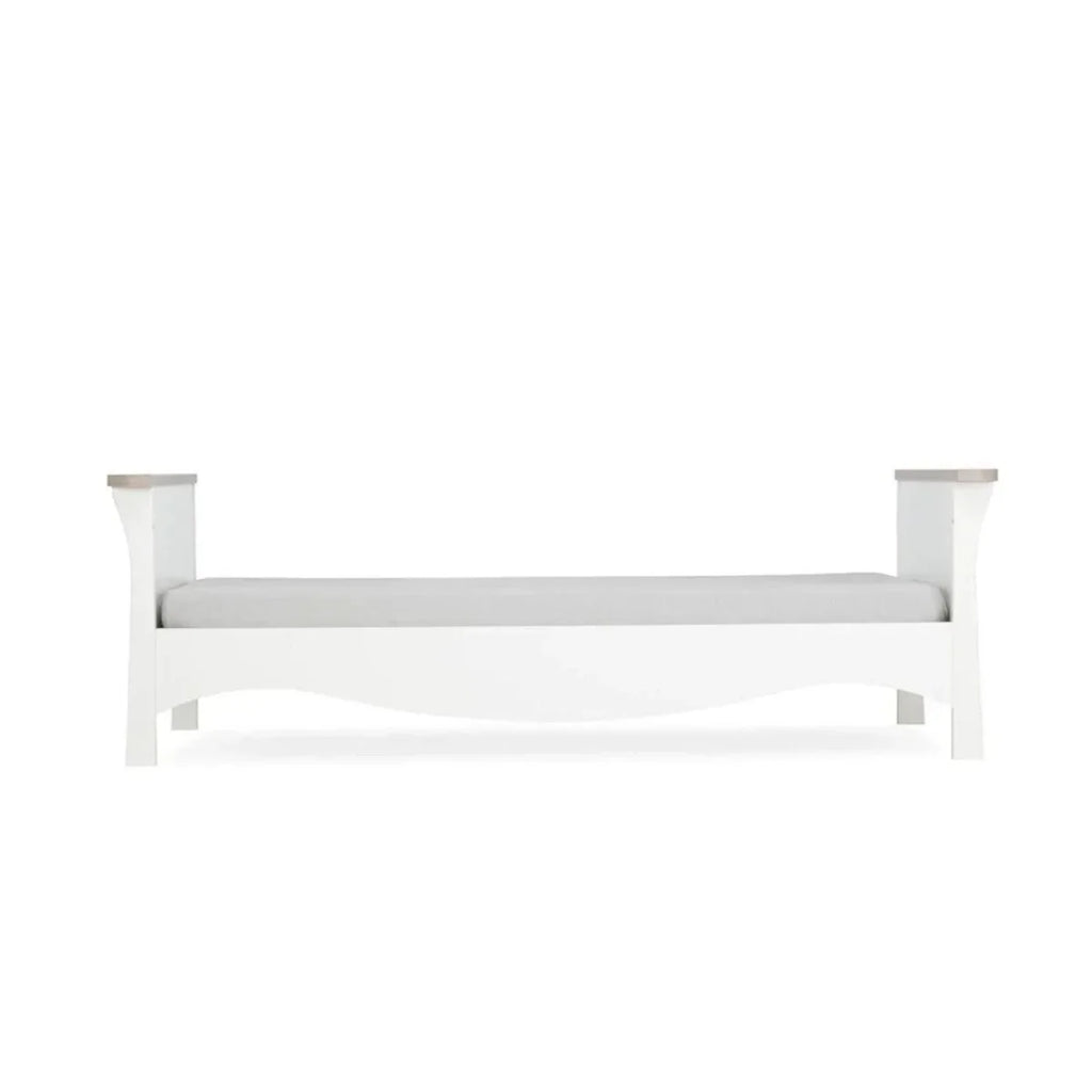 White nursery crib with horizontal top rail and mattress platform
