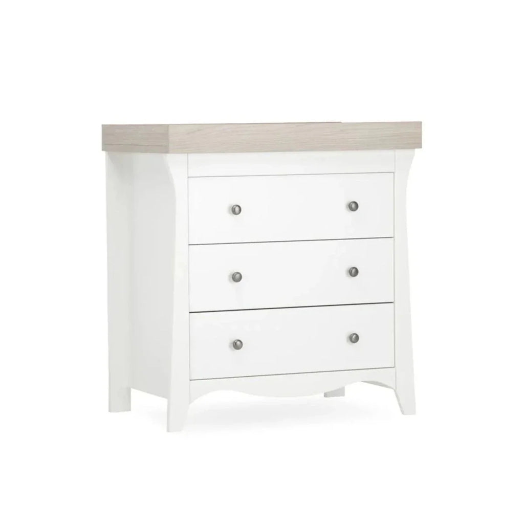 White nursery dresser with three drawers and ash-toned top panel