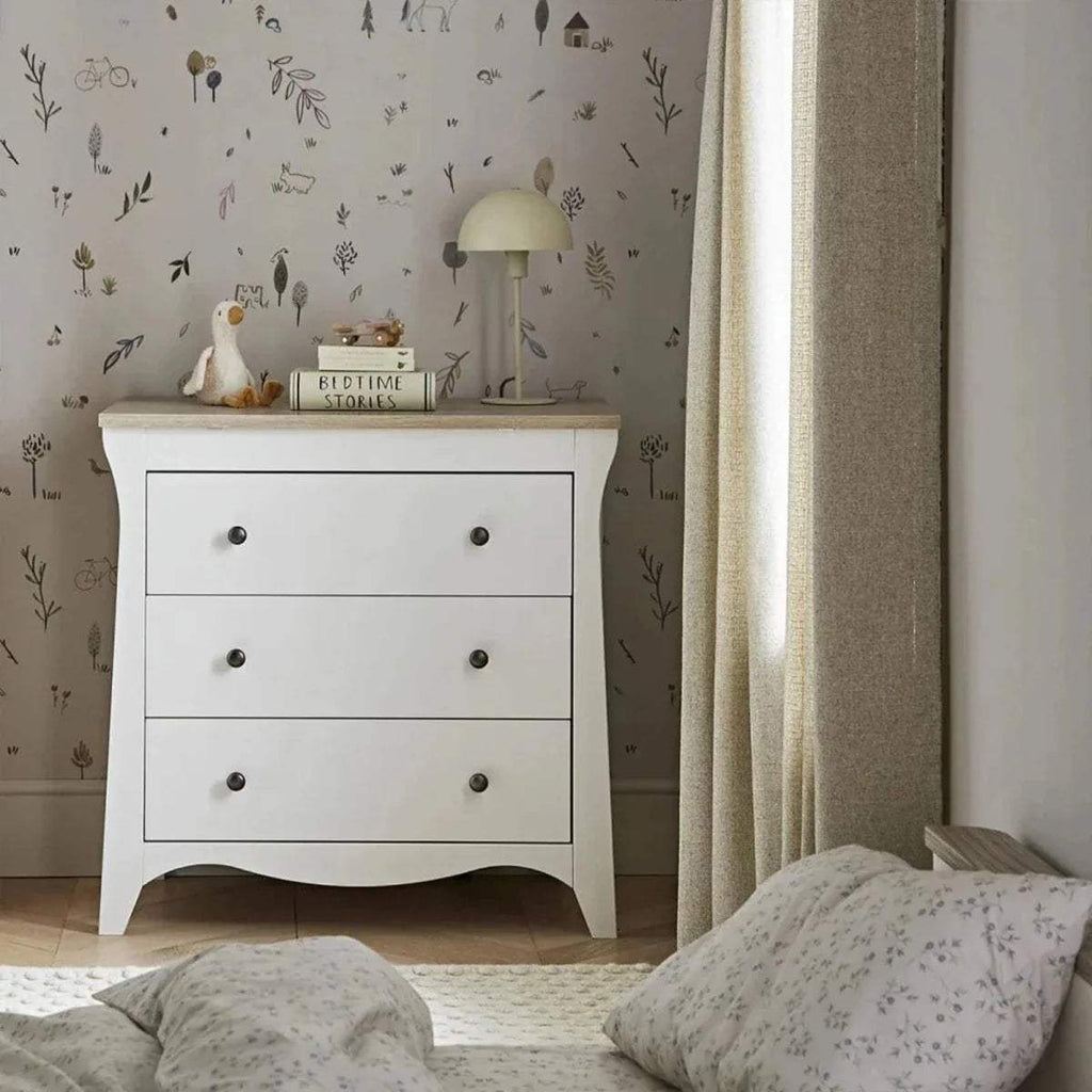 White 3-drawer dresser changer with curved base, three drawers, and metal knob pulls