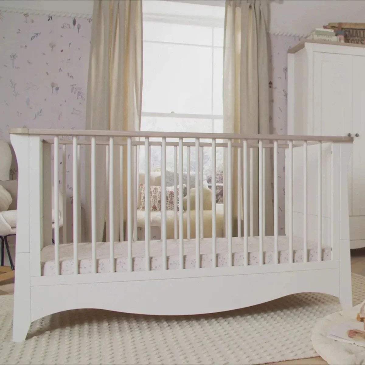White cot bed with vertical bars, curved base, and light ash top rail