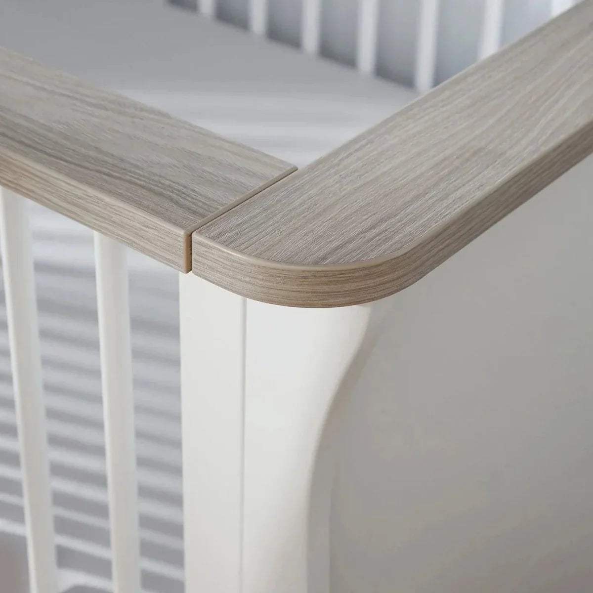 Cot bed corner detail with light ash rounded rail and white frame