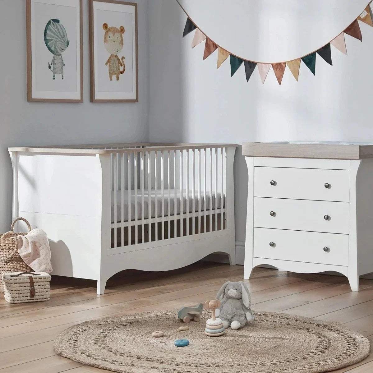White cot bed with vertical slats and curved base, shown with padded mattress