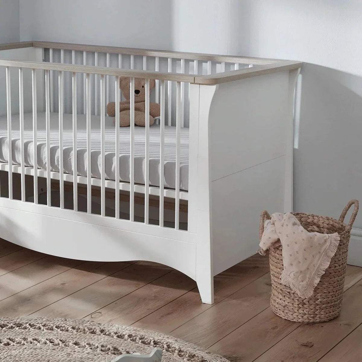 White cot bed side view with vertical slats and curved base lower panel