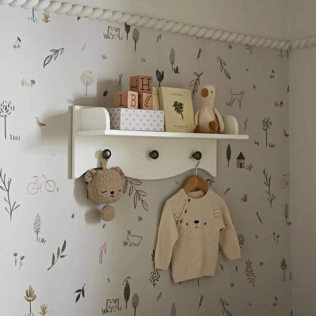 White kids wall shelf with top ledge, 3 round knobs, and hanging rail for clothes