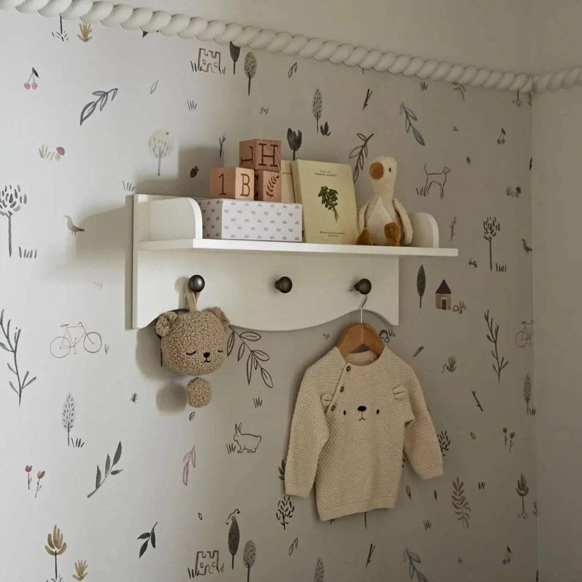 White kids wall shelf with top ledge, 3 round knobs, and hanging rail for clothes