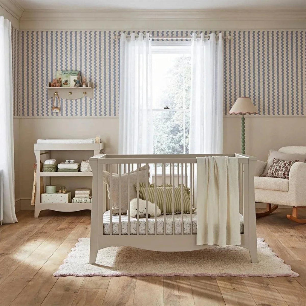 Nursery crib with slatted sides and cream duvet, set on a light rug