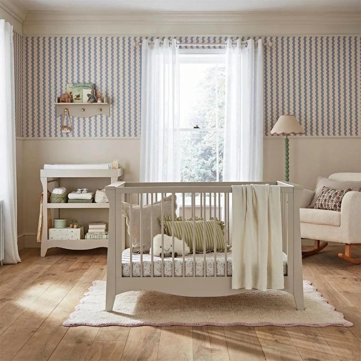 Nursery crib with slatted sides and cream duvet, set on a light rug