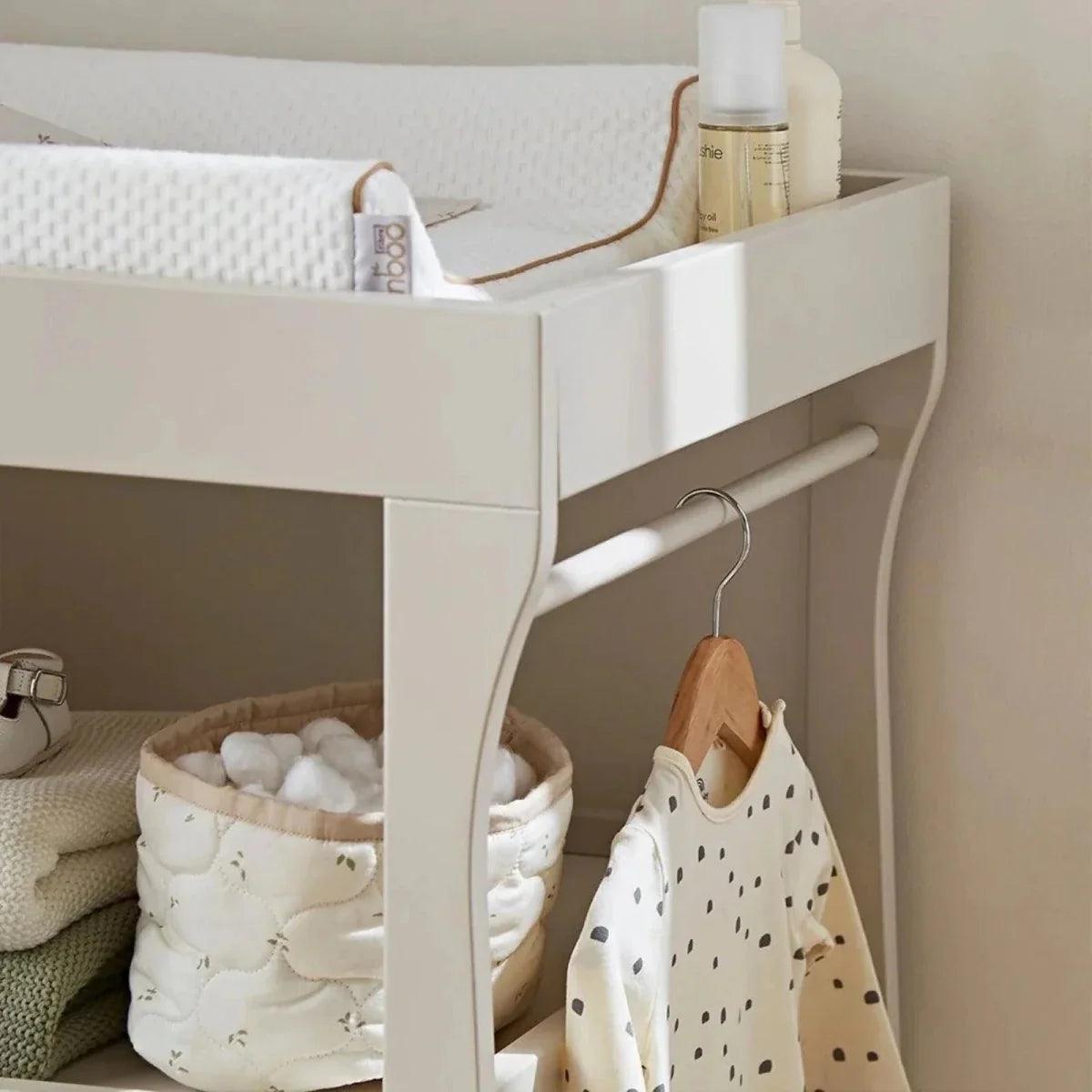 White nursery mini bed with slatted sides and attached storage drawer