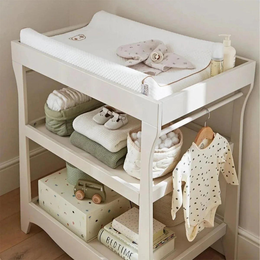White mini baby changing unit with padded top mat and two storage levels