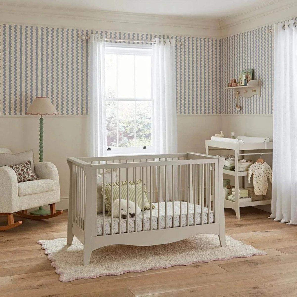 White mini cot bed with vertical slats and curved footboard, plus fitted mattress set