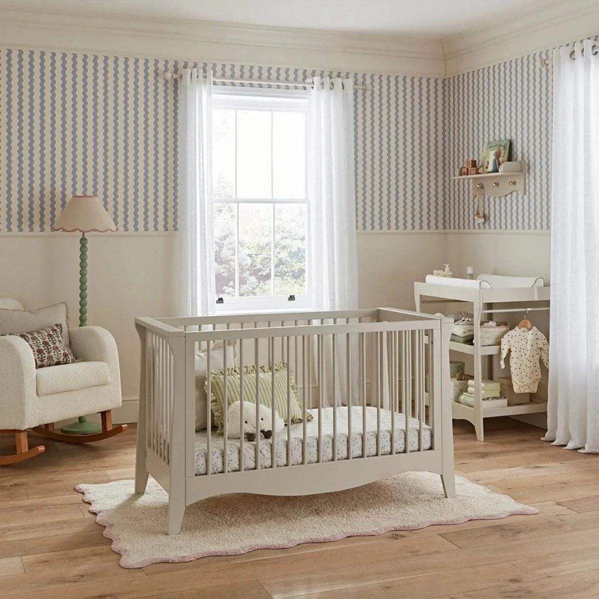 White mini cot bed with vertical slats and curved footboard, plus fitted mattress set