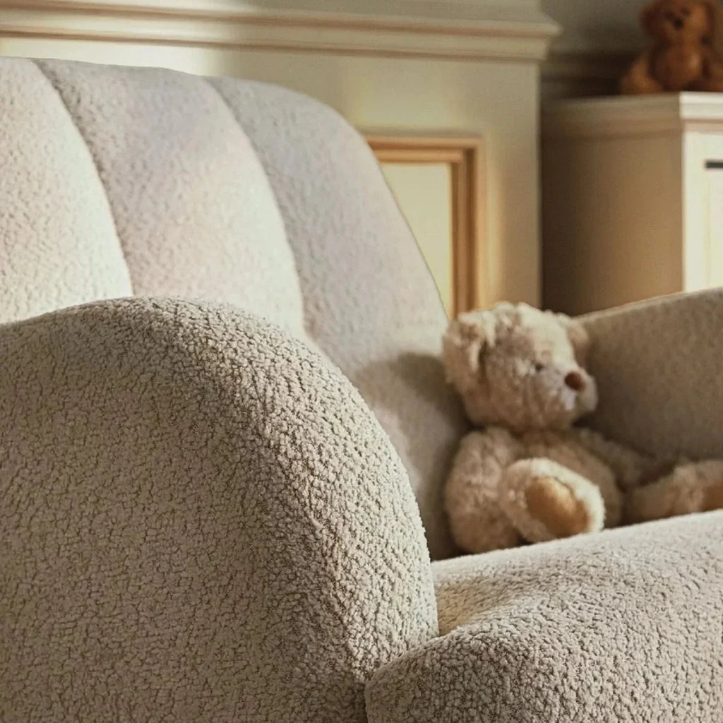 Light beige boucle nursing chair with teddy toy on seat, close-up of arm and back