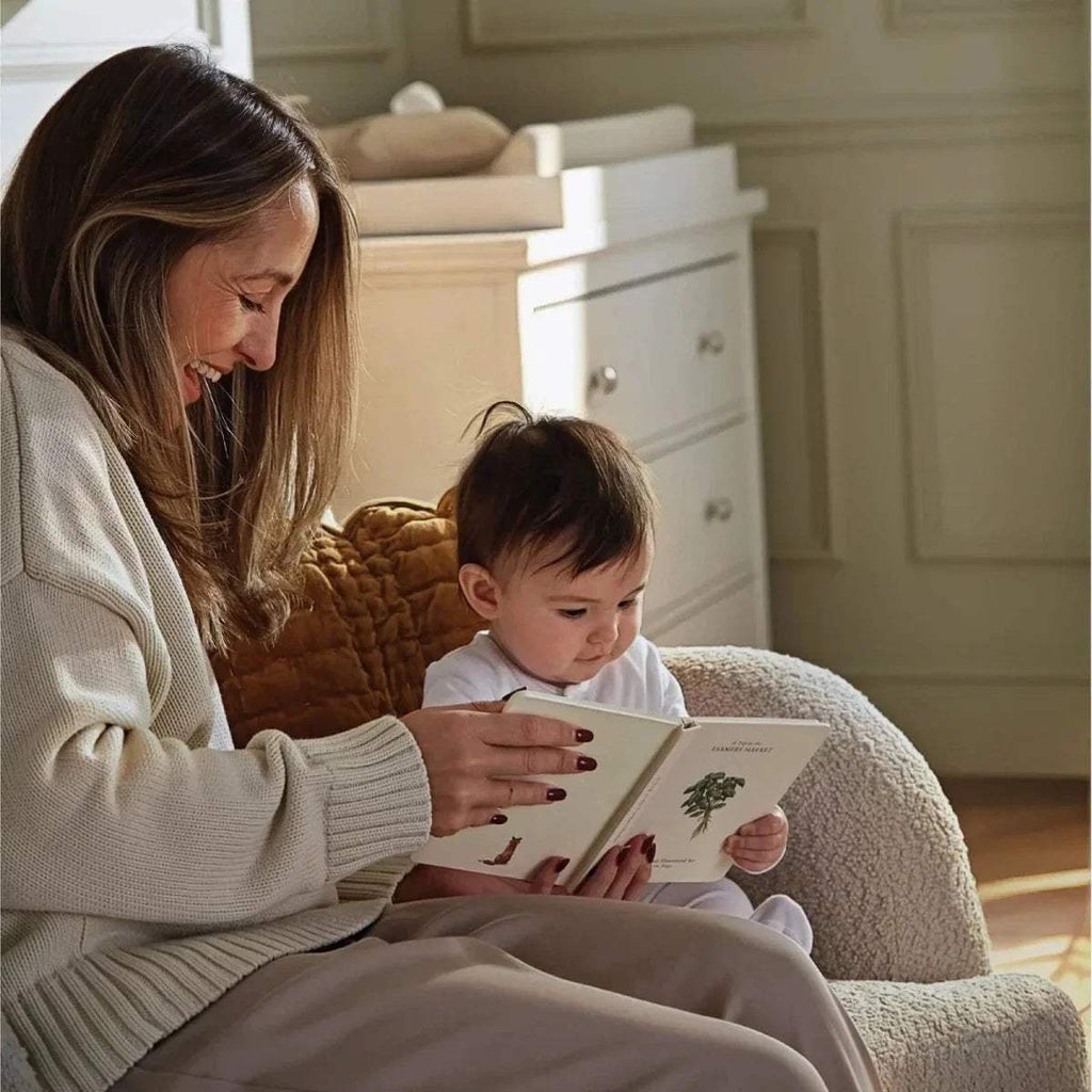 Off-white boucle nursing chair with cushioned armrests and supportive seat