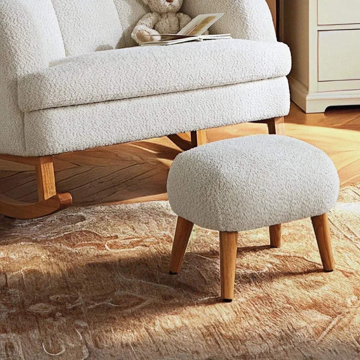 Off-white boucle nursing chair with rocking base and round ottoman foot stool