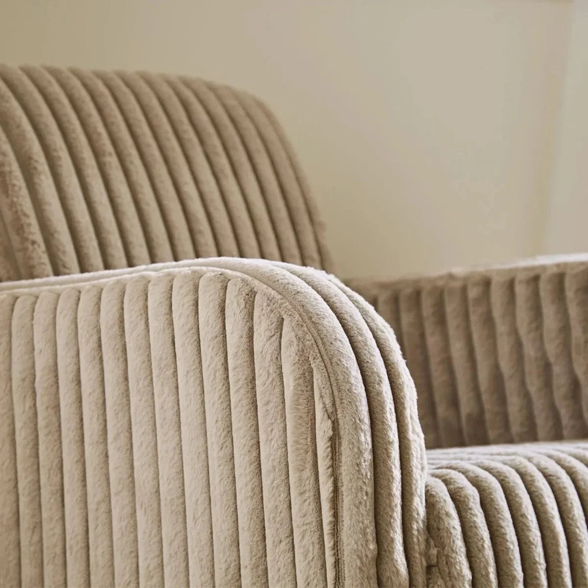 Close-up of mink ribbed faux-fur nursing chair arm and backrest with rounded padded edges.