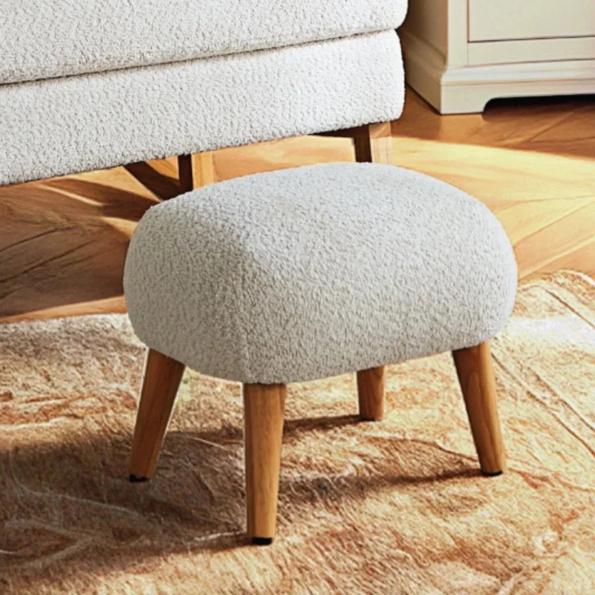 Round boucle ottoman foot stool with mushroom beige fabric seat and tapered wood legs.
