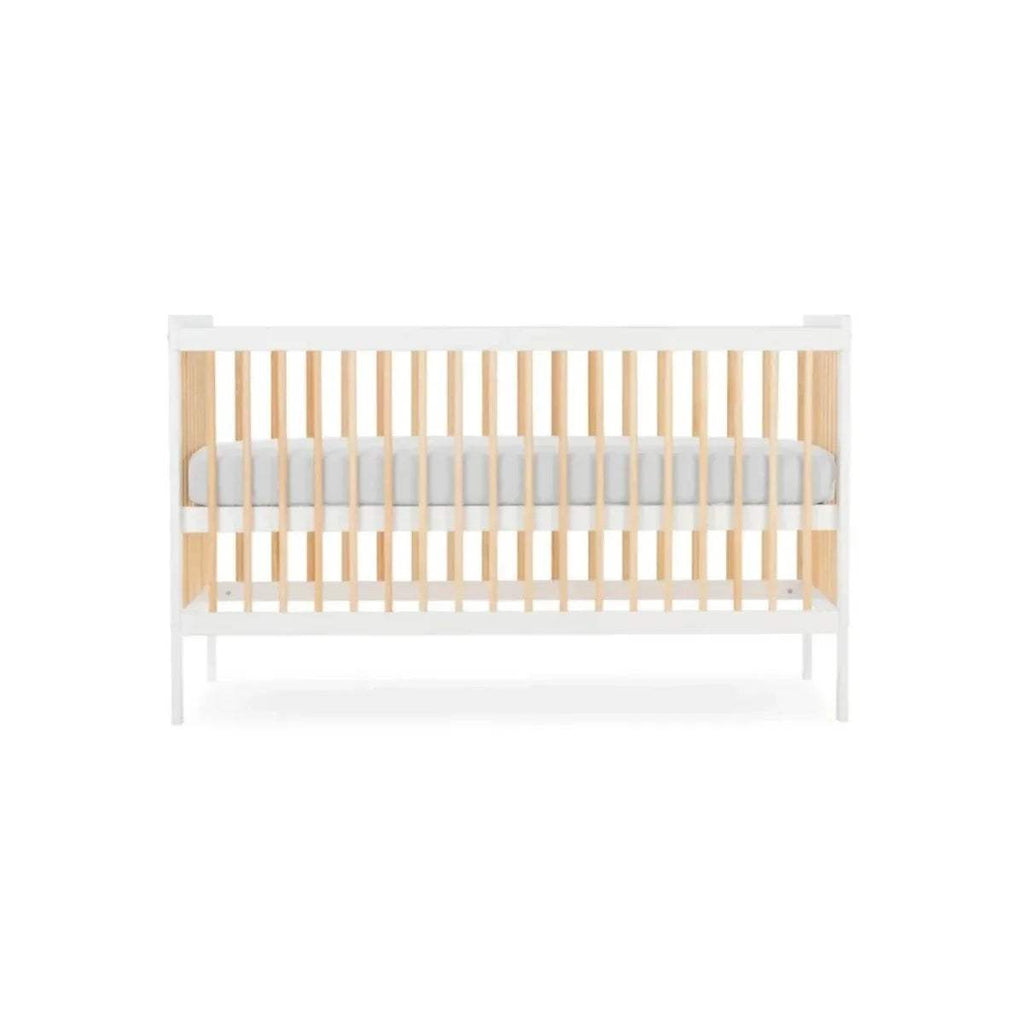 White cot bed with natural vertical slats and light grey mattress insert, side view.